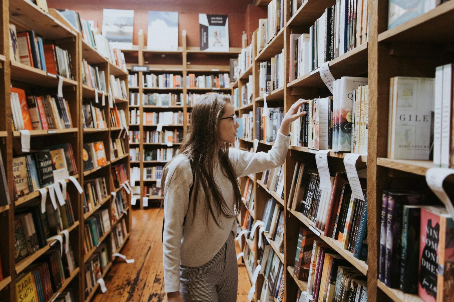 A woman picking a book from a shelf