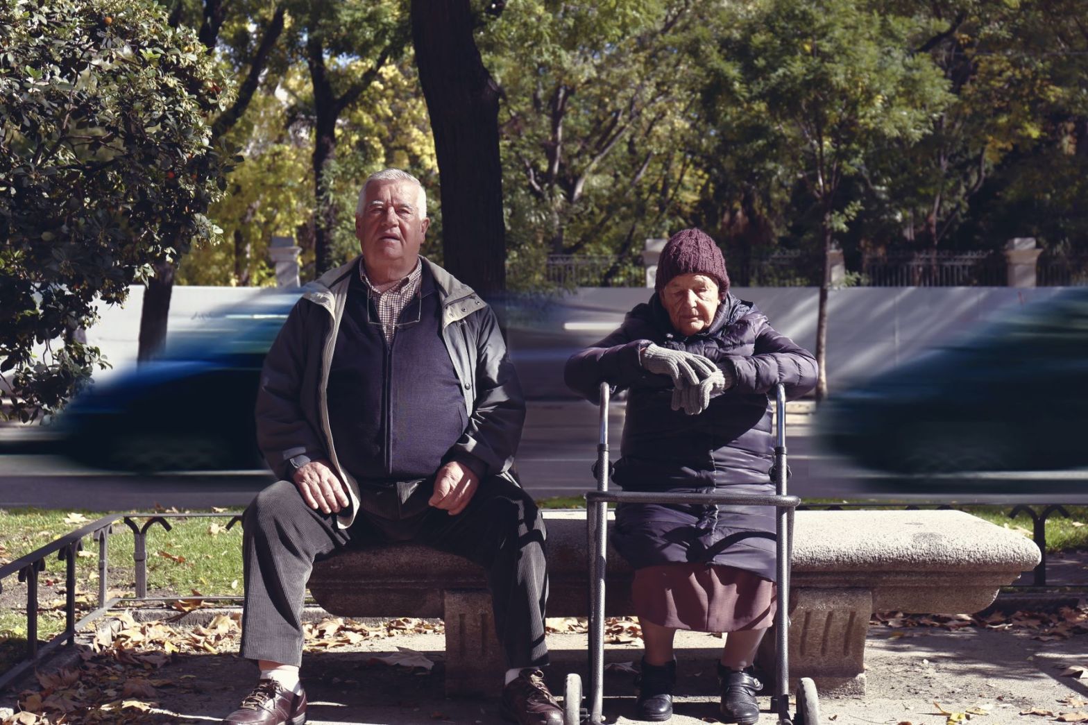 old man and woman sitting on a parked bench